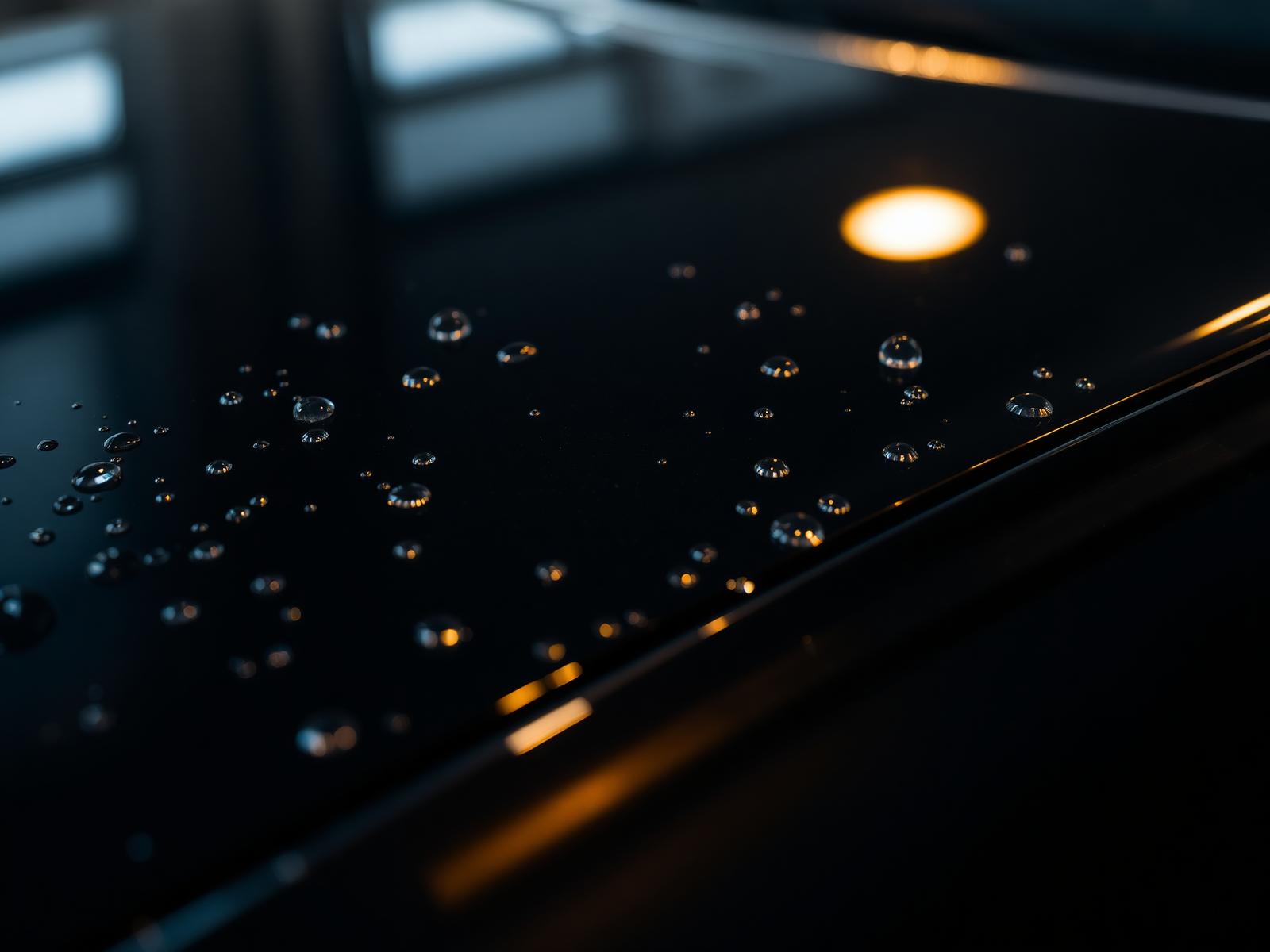 Mirror-finish black car hood with water beading